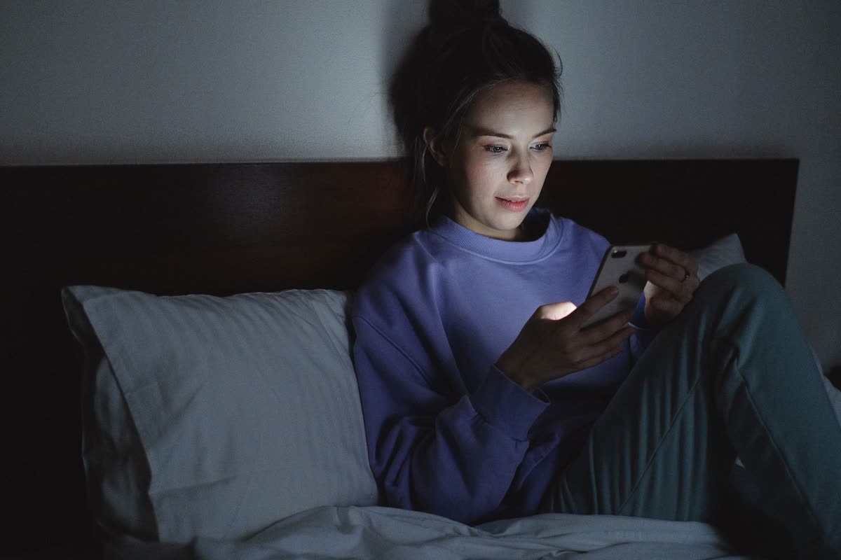 A woman using her phone in bed in the evening